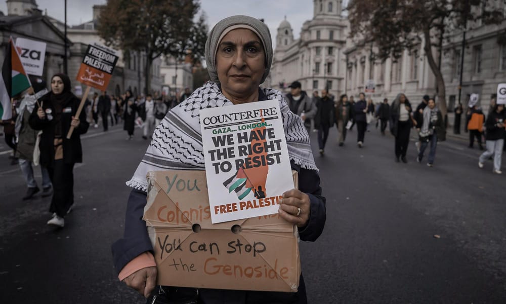 A Palestinian protester in London holding a sign that reads "We have the Right To Resist, Free Palesine"