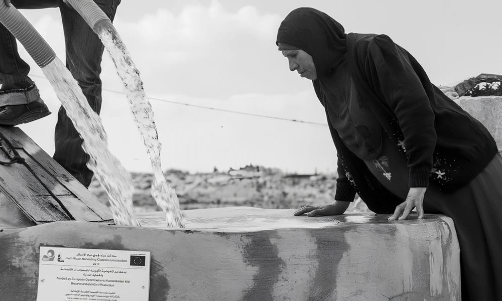 Palestinian woman looks into a well in the occupied West Bank