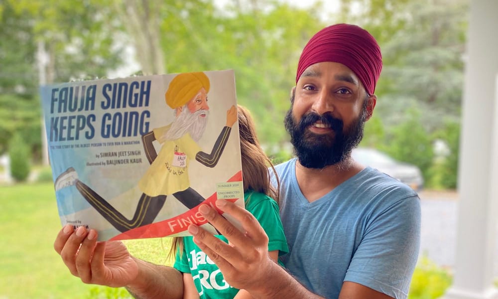 A photo of author Simran Jeet Singh happily holding his first illustrated children’s book.