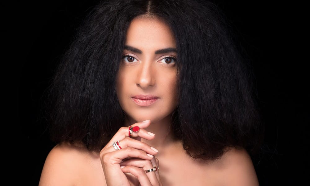 A portrait photo of Harvinder Keila, wearing the rings she made and designed.