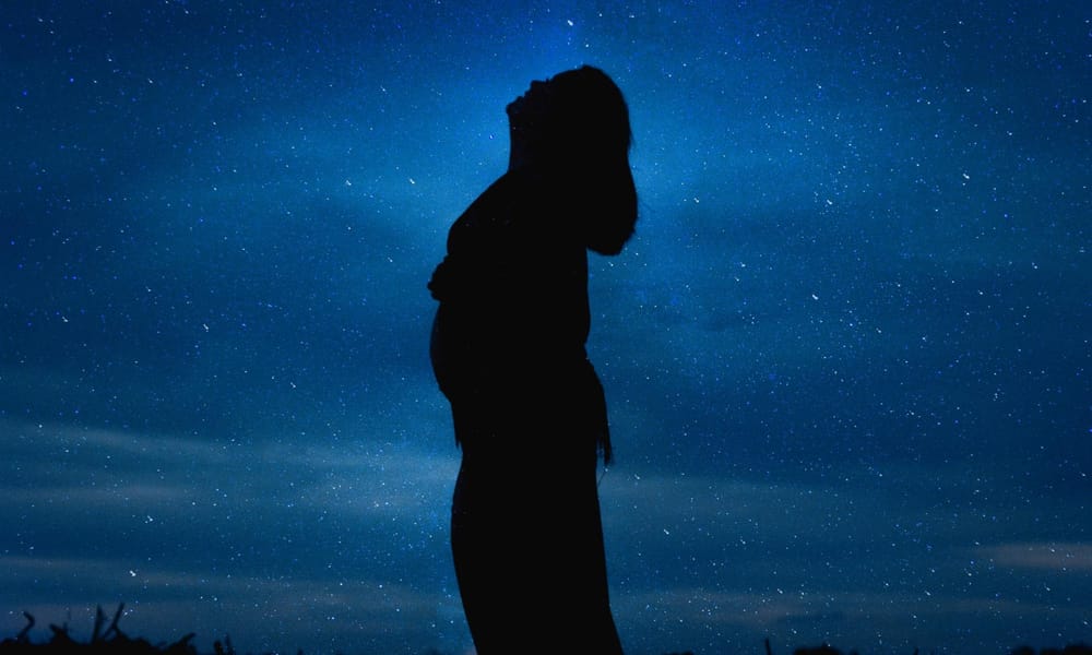 A photo of the woman's showing her standing under the night sky.