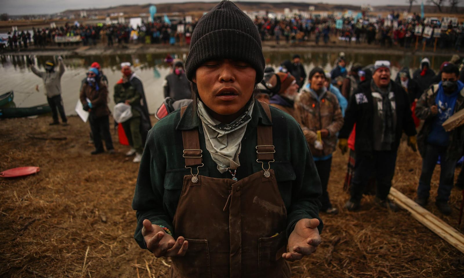 A photo of indigenous people standing by a river and singing in protest.